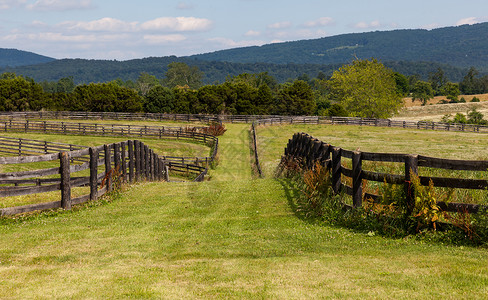 绿草牧场背景有木围栏和山丘图片
