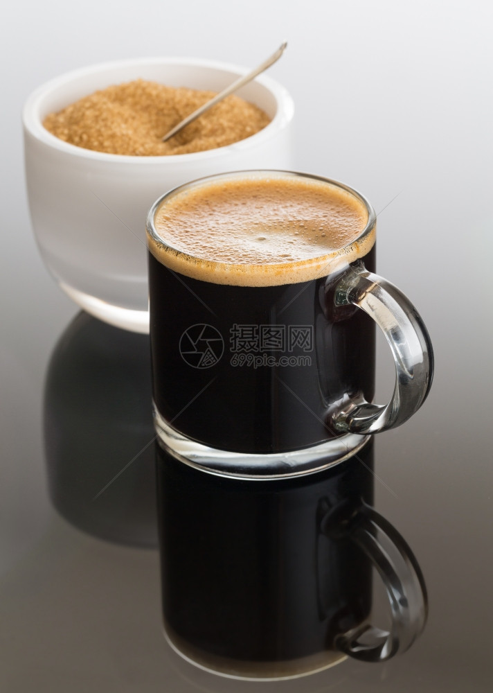 小玻璃杯中的黑面咖啡白碗中的糖反映图片