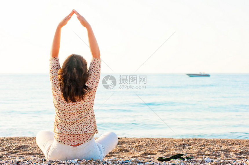 Pilates女孩坐在沙滩上图片