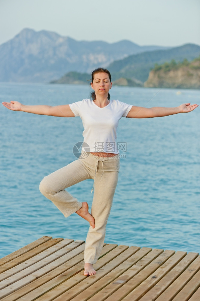 女孩站在码头的一条腿上保持平衡图片
