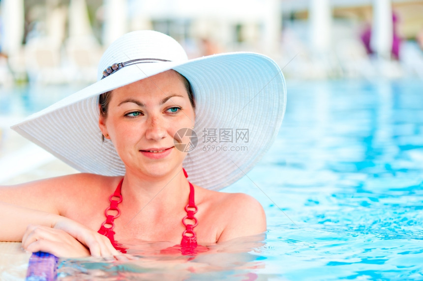 在度假村游泳池里放松的年轻女子图片