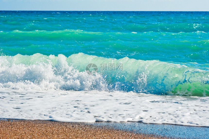 强烈的泡沫波浪拍打在海滩图片