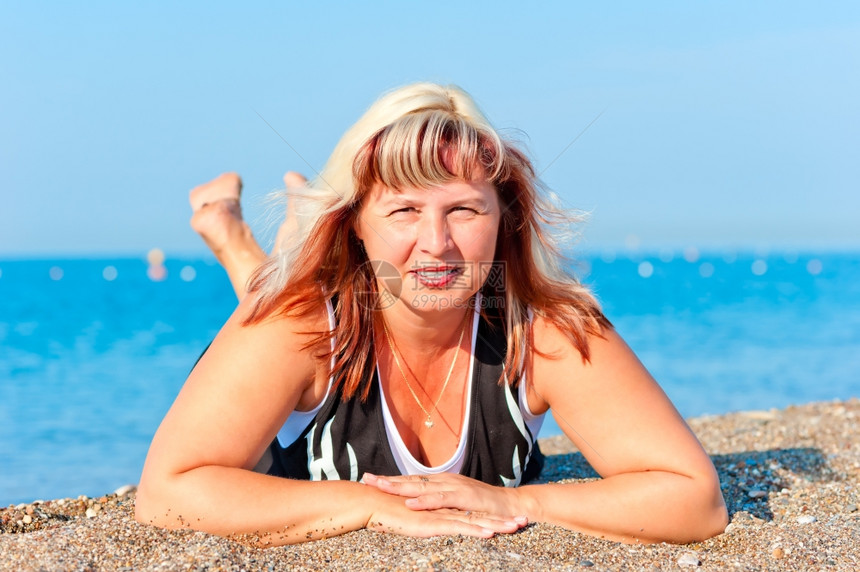 年轻美丽的祖母睡在沙滩上图片