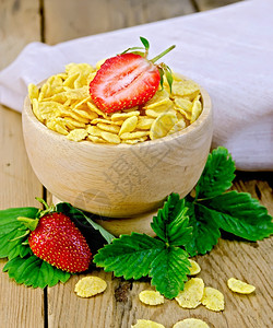 木碗中的玉米花草莓叶和浆果木板上的餐巾纸背景图片