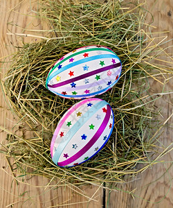 以两只东鸡蛋装饰上面木板背景的干草上装饰多彩的胸罩和火花星号图片