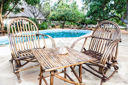优雅的椅子由木制靠近Kenya花园里的游泳池图片