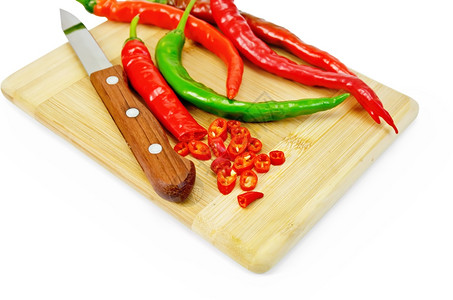 红色和绿辣椒用一把刀在个木板上的孤立在白色背景上图片