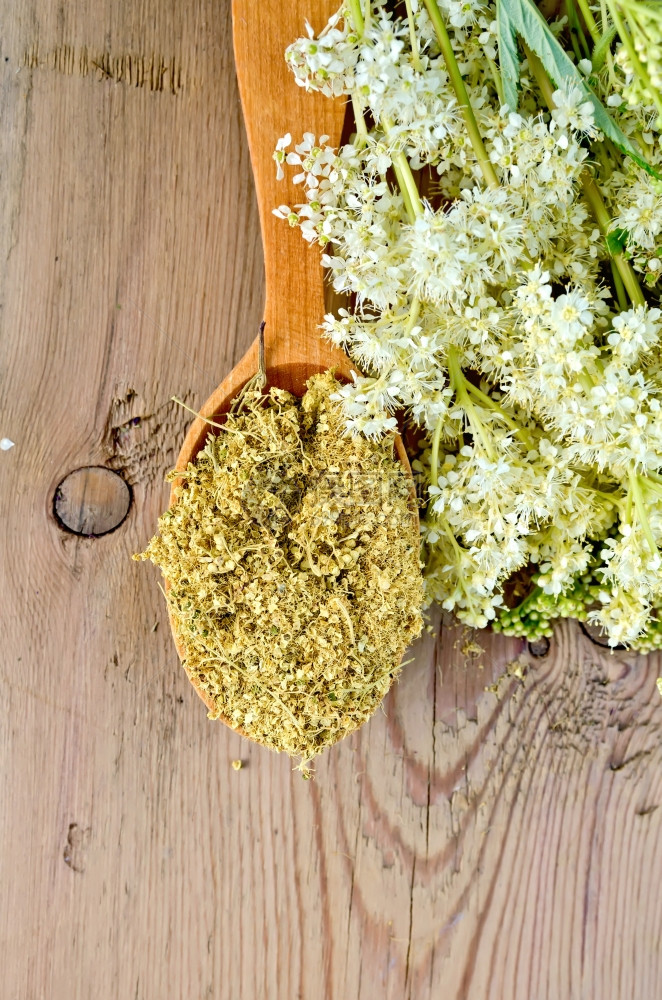木制勺子配有干枯的草地蜂蜜花朵木制板上一束草地蜂蜜鲜花图片