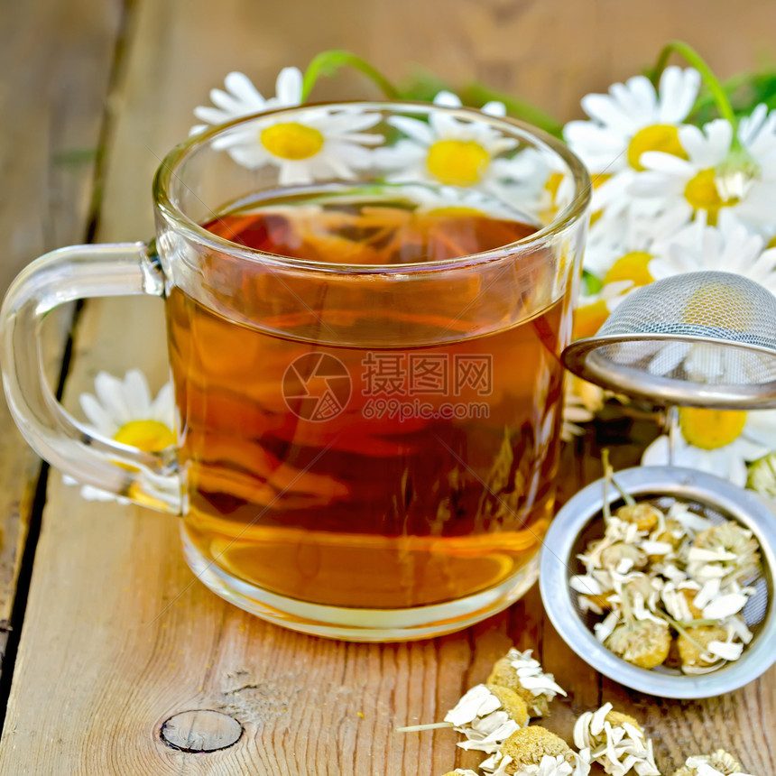 茶杯中的金属筛子含干甘菊花木板背景上的一束鲜花朵图片