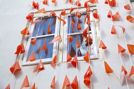 沿着白色墙壁和反映蓝天空的窗口横线排列橙旗高清图片