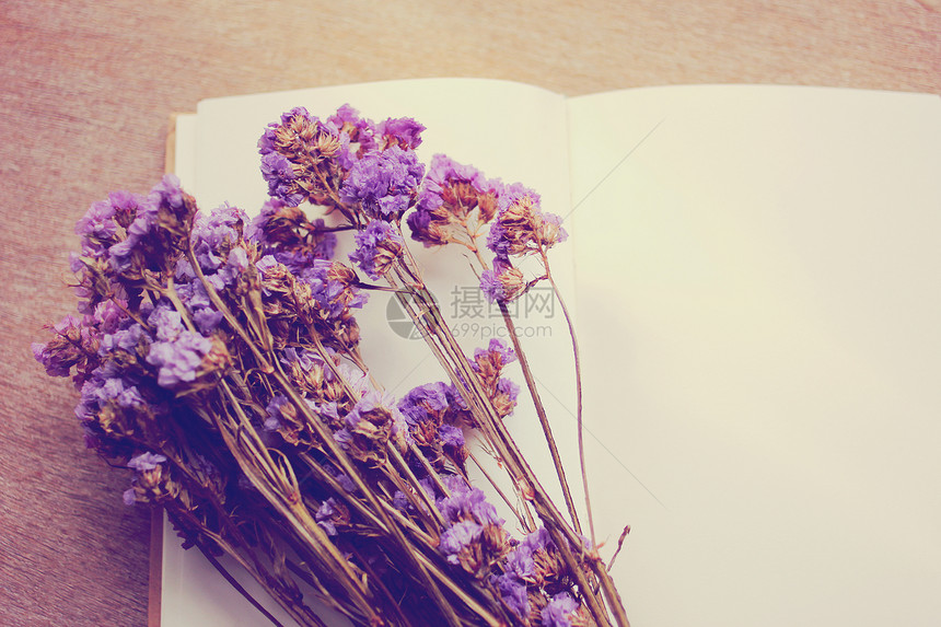 白色笔记本上的紫色干花图片
