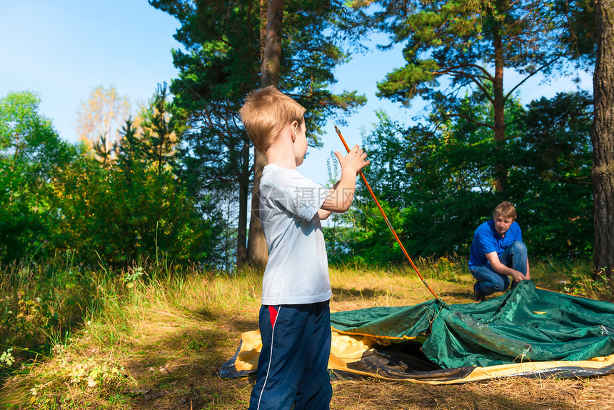 小儿子帮助在大自然上搭帐篷图片