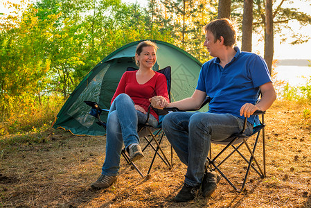 坐在帐篷旁边的年轻美夫妇背景图片