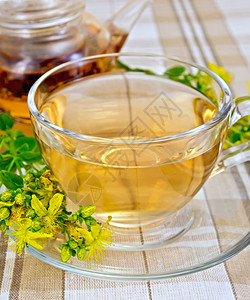 杯子和茶壶里的草药衣服桌布背景上鲜花图片