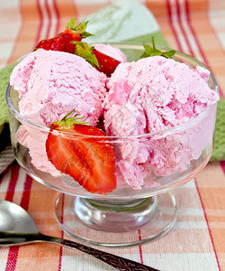 草莓和的玻璃碗中冰淇淋餐巾纸上的勺子桌布背景图片