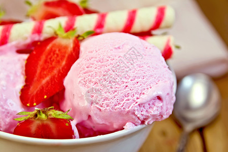 白碗中的草莓冰淇淋和面包卷木板上的餐巾图片