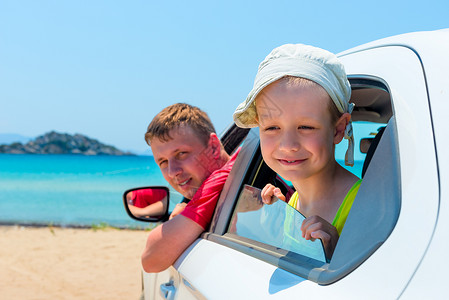小男孩和他父亲坐在沙滩上的一辆车里图片