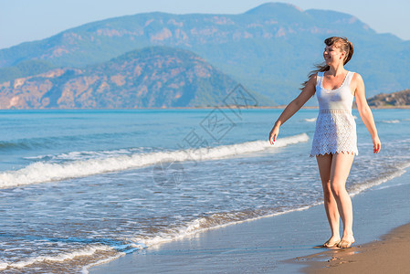 在海滩上赤脚走路的快乐女孩图片