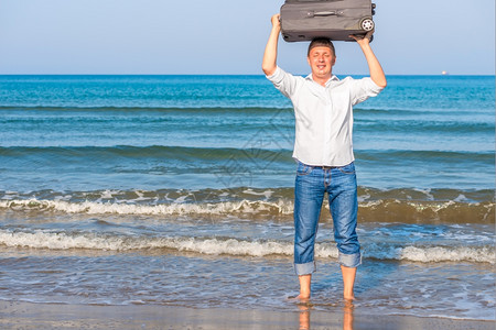 光脚在海中拿着手提箱的快乐男人图片