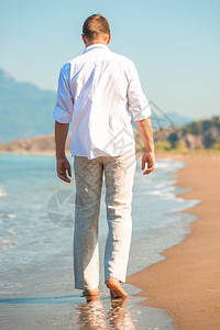 穿着白衣男子在海滩上行走图片