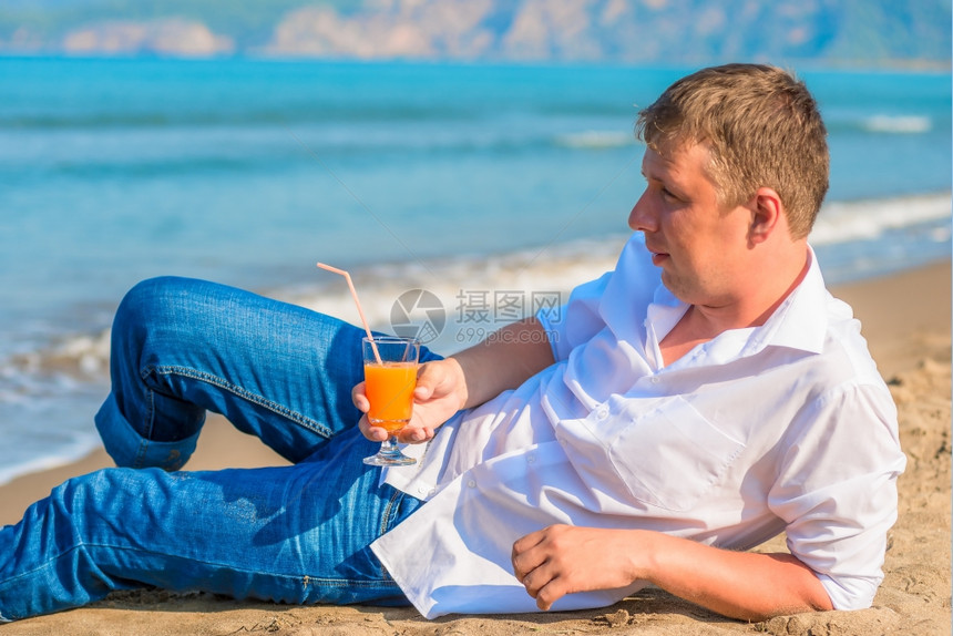一个男人穿着衣服躺在沙滩上穿着鸡尾酒图片