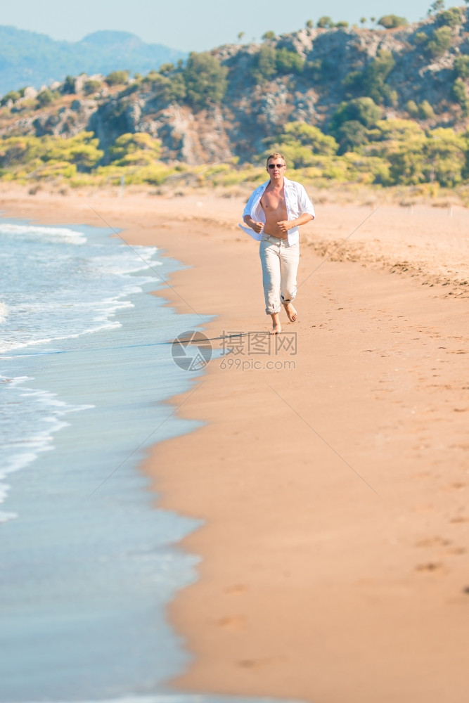 男人沿着海滩跑步图片
