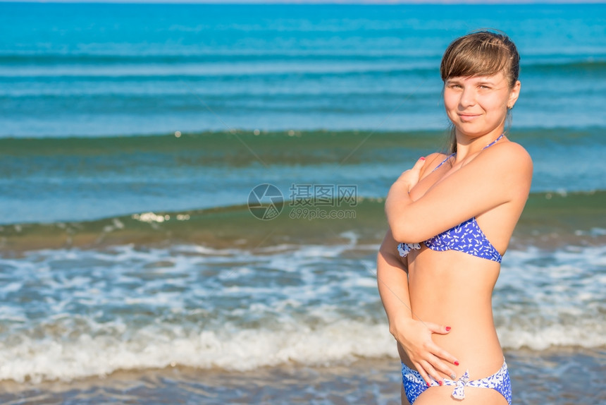 穿着泳衣的可爱年轻女孩在海边摆姿势图片
