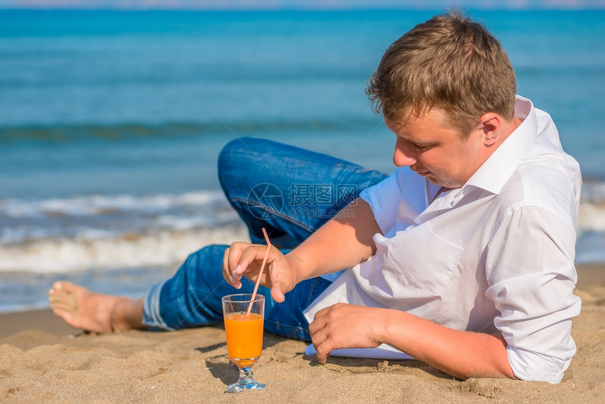 成功的年轻人在海边休息喝鸡尾酒图片
