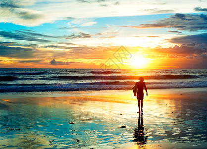 日落时光在海滩上行走的冲浪者图片