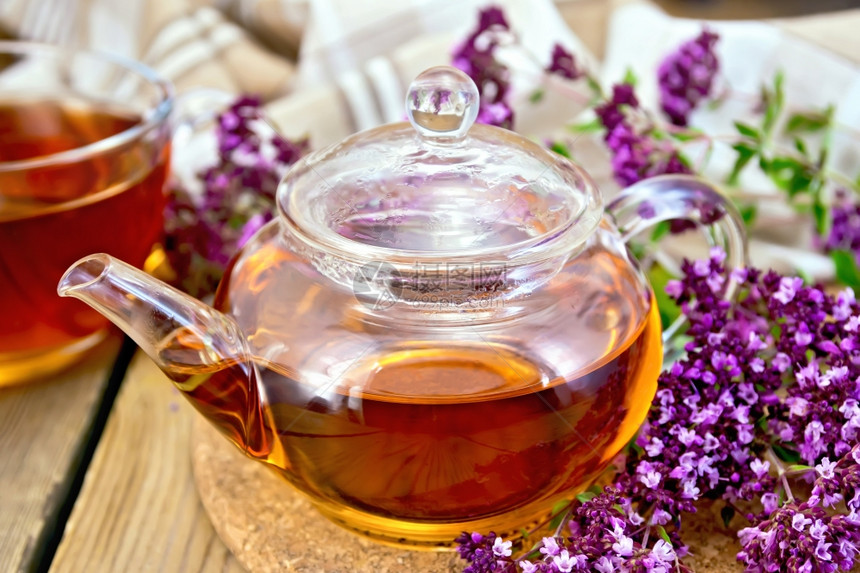 茶壶和杯子里的草药茶鲜花木板上的餐巾纸图片