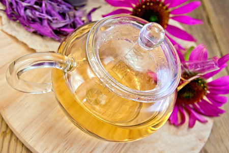 玻璃茶壶中的草药叶木板背景上的新鲜和干燥石茶花图片