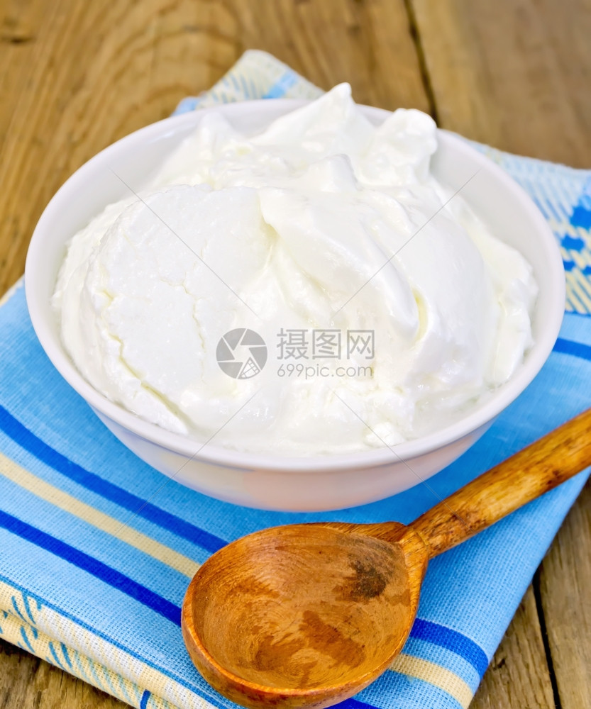 白碗里厚的酸奶勺子木板上餐巾纸图片