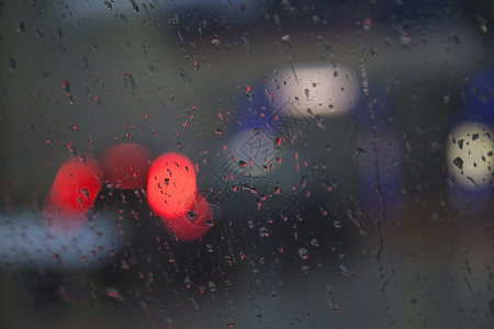 降雨量降雨时通过湿挡风玻璃看见的红色交通灯背景
