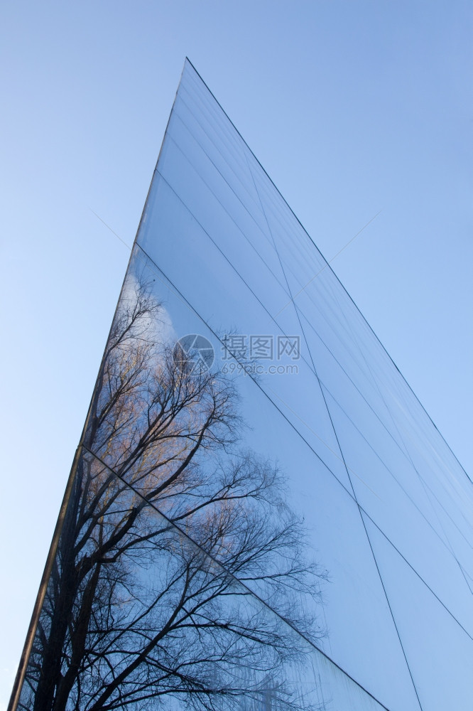 现代办公大楼的玻璃面罩和树木蓝天空的反光图片
