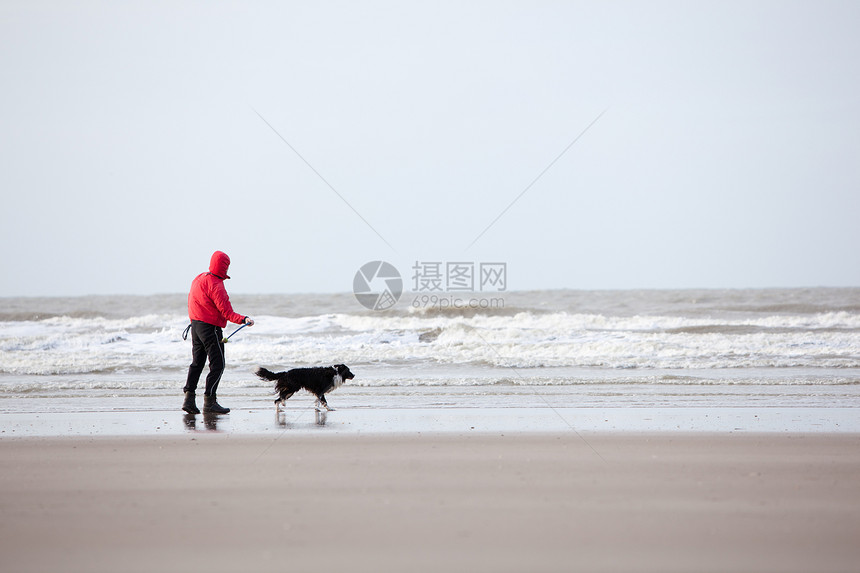 男人和狗在风沙滩上图片