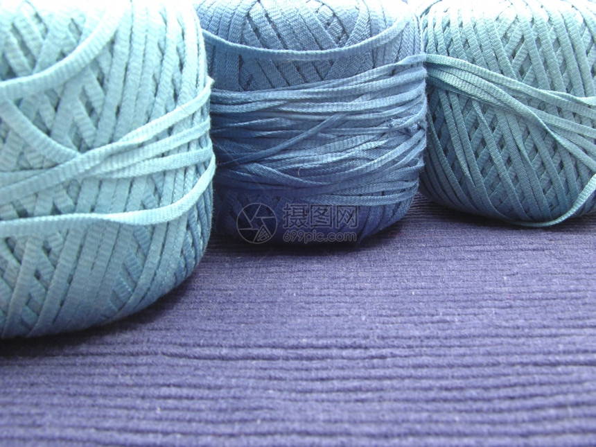 3个蓝色羊毛球用于在蓝色地垫上安排的针织图片