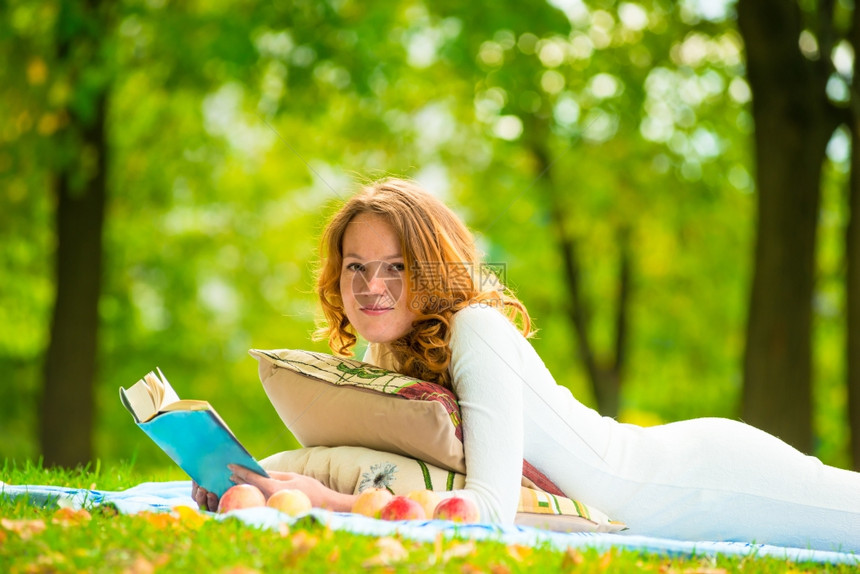一位美丽的学生肖像画在一个夏季公园与一本书图片