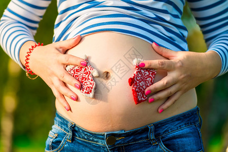 年轻孕妇肚子和编织的手套图片