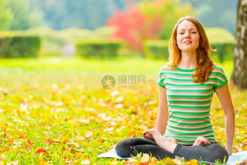 穿绿T恤女孩在秋天公园做瑜伽图片