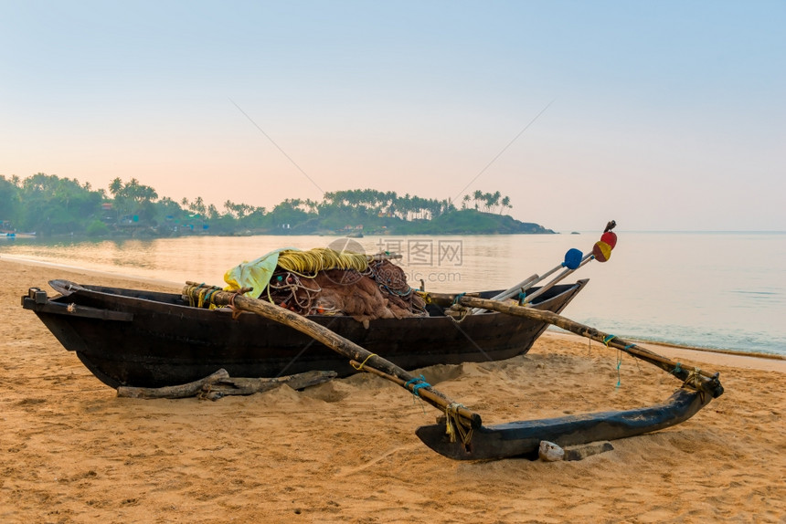 海滩上黎明时的木制渔船图片