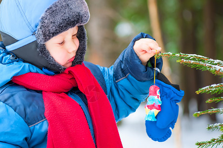 男孩挂在森林的圣诞树装饰上图片