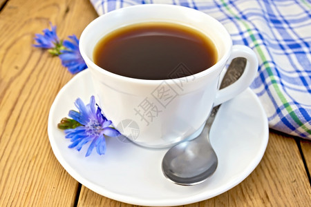 茶托勺子在一个白色杯子里喝葡萄酒在碟子和勺上花朵在木板用餐巾纸背景