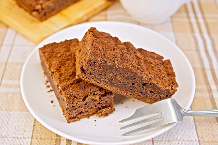 两块巧克力蛋糕放在盘子上叉放在桌布的背景上图片