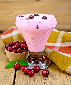 在玻璃杯子里的厚酸奶里面有红莓餐巾纸碗中的红莓木板底的薄荷图片