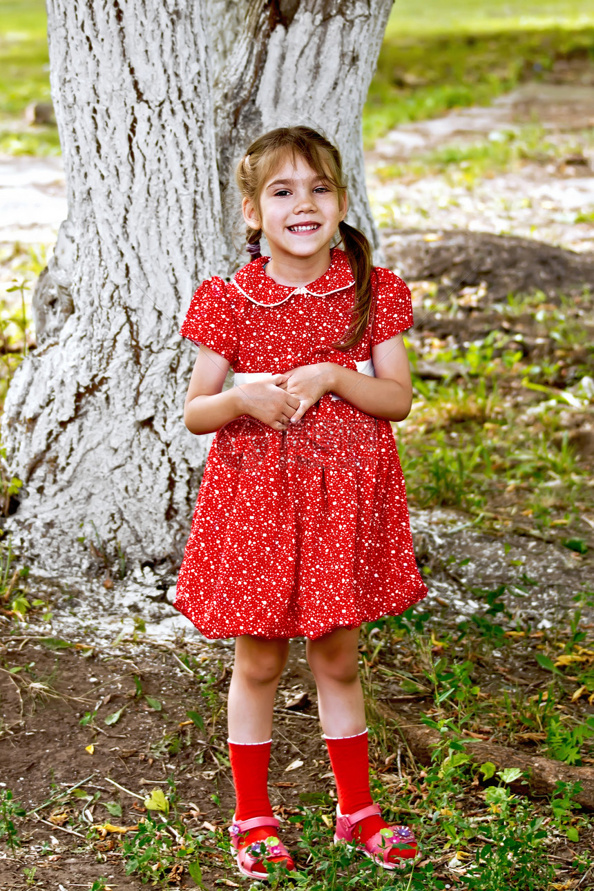 身着红礼服的女孩在绿草树下图片