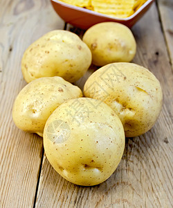 5个新鲜的黄色土豆管木板底的粘土碗中薯片图片