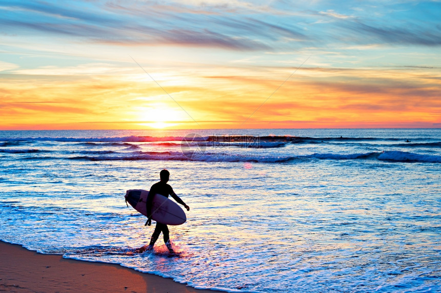 日落时在海滩散步的冲浪机图片
