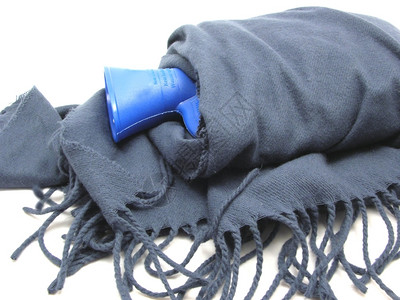 蓝色热水袋包裹在带边缘的蓝色围巾上图片