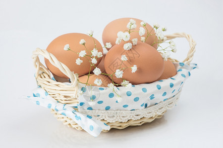 两个新鲜的鸡蛋和白花放在一个柳条篮子里图片