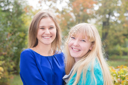 两个微笑的年轻女孩肖像在秋天自然特写图片